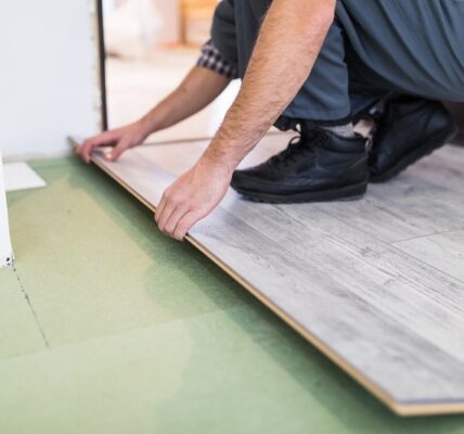 worker processing a floor with laminated flooring boards