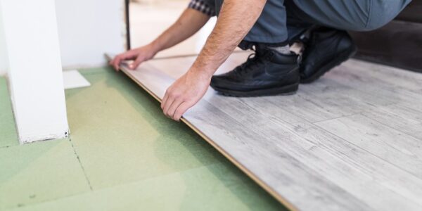 worker processing a floor with laminated flooring boards